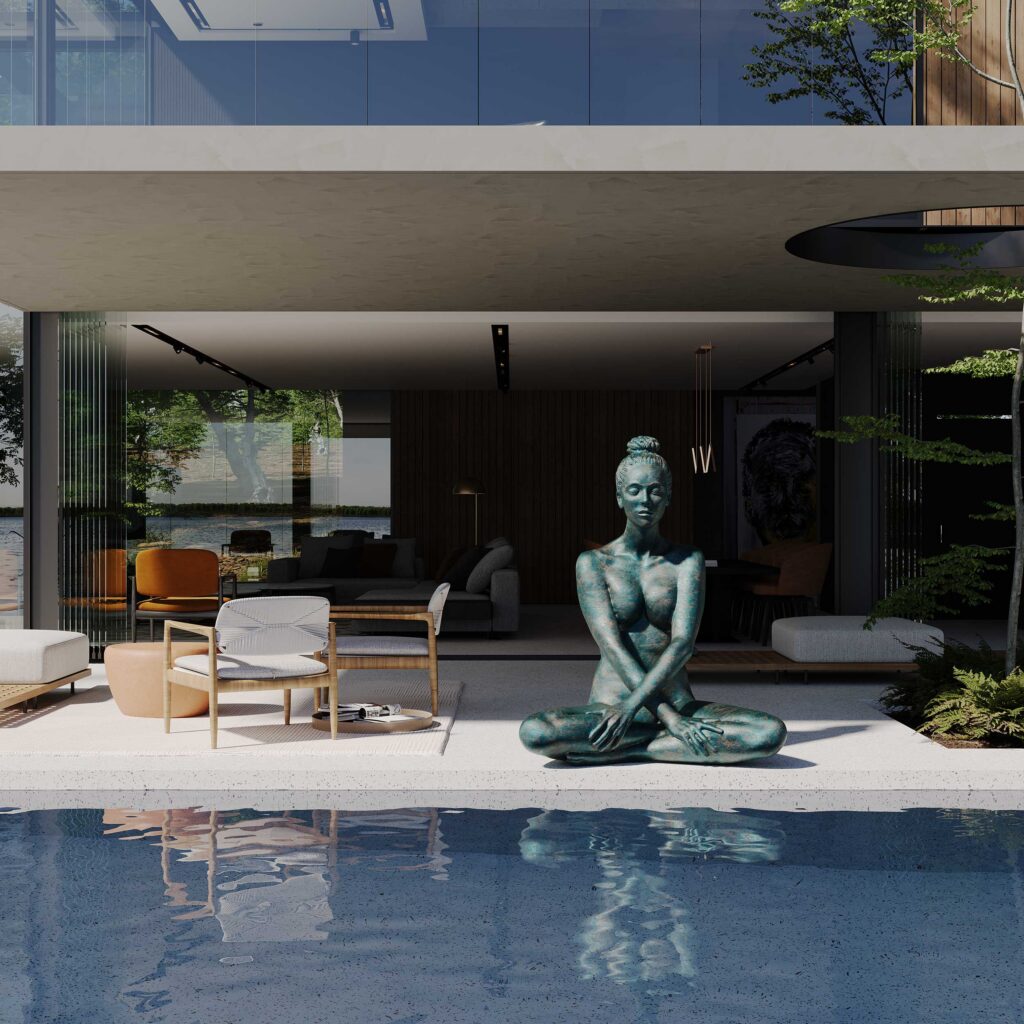 Villa Nandoni – lakeside pool deck with a seated bronze meditation sculpture beside a glass-walled lounge featuring rattan and orange armchairs, opening onto water and tree views.